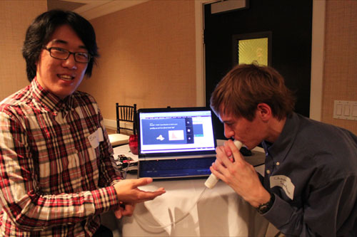 Jungwoo Lee explains how his team?s Windows Phone game Azmo the Dragon helps children manage their asthma while teammate Chase Sandmann blows into a digital spirometer to measure his lung capacity.