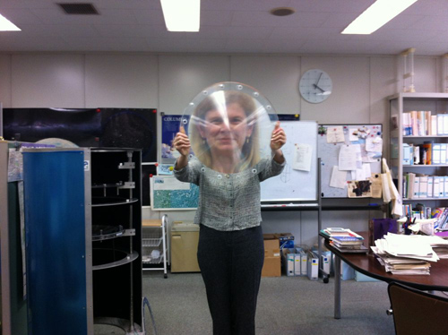 Prof. Angela Olinto, chair of astronomy & astrophysics, leads the U.S. collaboration of an international effort to study ultra high-energy cosmic rays from the International Space Station. Here she peers through a prototype Fresnel lens developed for the Extreme Universe Space Observatory, which will incorporate three such lenses to allow the best efficiency for the widest field of view. Image courtesy of Angela Olinto