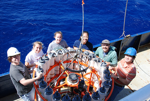 Wang, far right, and his students and lab members (clockwise from far left, Elliott Roberts, Kelly Knorr, Katherine Hoering, Sophie Chu, and Nick Tuttle) at sea around a CTD rosette.  CTDs measure conductivity or salinity, temperature, and depth and are a common tool of oceanographic research. Water samples are collected in each of the rosette’s canisters at various depths and then chemically analyzed in the lab. (Photo by Taylor Crockford, Woods Hole Oceanographic Institution)