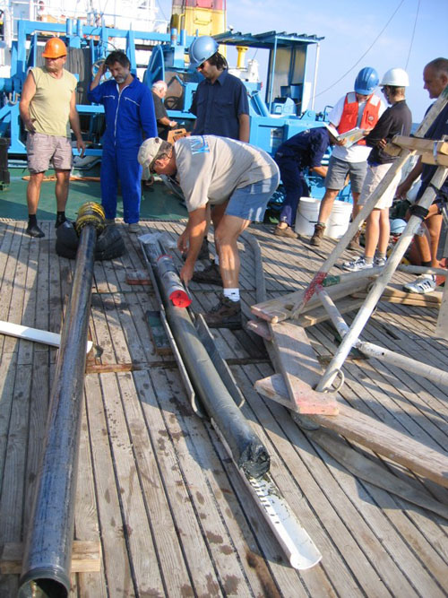 WHOI researcher Alan Gagnon, Marco Coolen (center, in blue safety helmet), and the crew from the Bulgarian research vessel Akademik sample the sediment core that was used for this study. (Photo courtesy of Dimitri Dimitrov from the Institute of Oceanology, Bulgarian Academy of Sciences (IO-BAS))