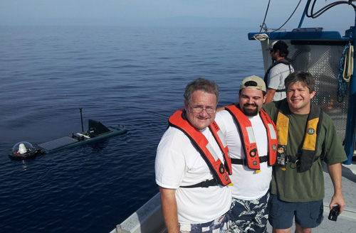 GTRI researchers (l-r) Jim Maloney, Matthew Habib and Gregory Kiesel pose with a Wave Glider autonomous marine robot during tests in the ocean off Hawaii. Image credit: Georgia Tech Research Institute (GTRI)