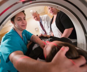 Technologist Diane Lemieux follows the red guide lights as she adjusts her patient's head for a pediatric CT scan. When a CT scan is still the best alternative, careful planning goes into minimizing radiation. Photo by Robert Lisak