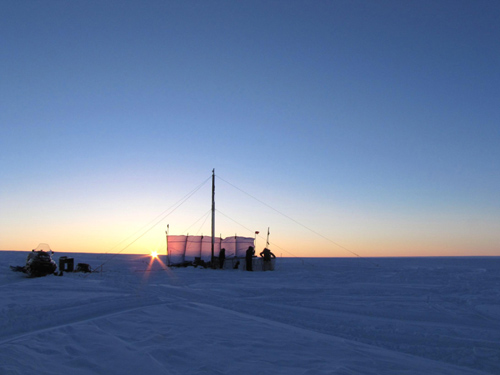 Drill rig used to extract firn cores from within the Greenland firn aquifer. One of the snowmobiles used in the 300 km traverse of the ice sheet to reach the drill site. Pictured, Clément Miège (co-author and PhD student University of Utah), and Terry Gacke (Ice Drilling Design and Operations). Photo Credit: Evan Burgess 