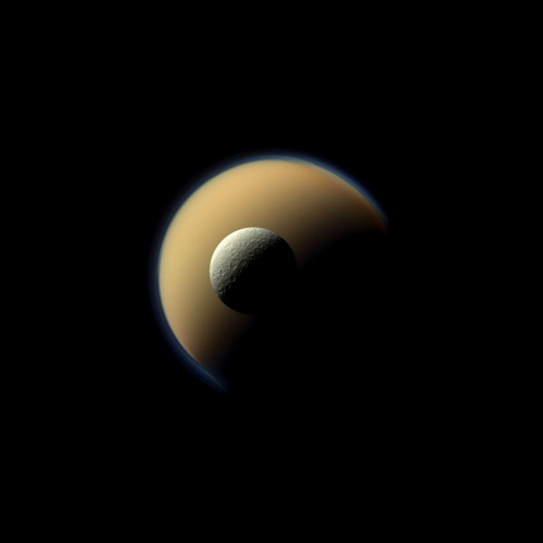 Saturn's largest and second largest moons, Titan and Rhea, appear to be stacked on top of each other in this true-color scene from NASA's Cassini spacecraft. Image Credit: NASA/JPL-Caltech/Space Science Institute