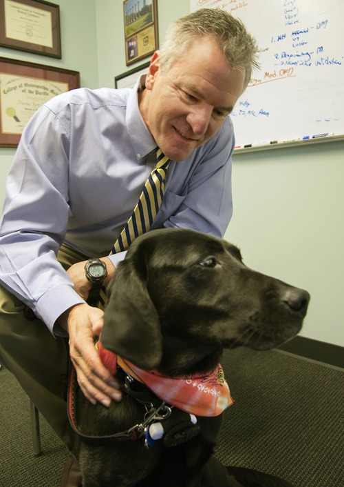 Gene therapy researcher Martin K. Childers with his family dog, Bella, who carries the gene for the disorder he studies. Image credit: Clare McLean