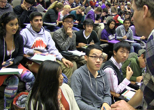 Freeman heads into the auditorium to help as students huddle trying to reason out an answer to a genetics question. Image credit: U of Washington