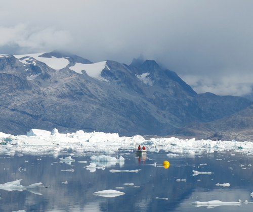 The deployment of a scientific mooring in Sermilik Fjord in August, 2011. The yellow buoyant sphere of the mooring can be seen floating on the surface with authors Rebecca Jackson and David Sutherland in the small boat behind. (Photo by Fiamma Straneo, Woods Hole Oceanographic Institution)