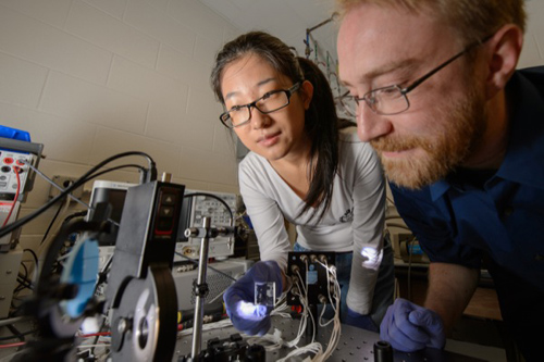 Yimu Zhao, a doctoral student in chemical engineering and materials science, and Richard Lunt, assistant professor of chemical engineering and materials science and a UD alumnus, run a test in Lunt’s lab. Lunt and his team have developed a new material that can be placed over windows and create solar energy. Photo courtesy of G.L. Kohuth, Michigan State University