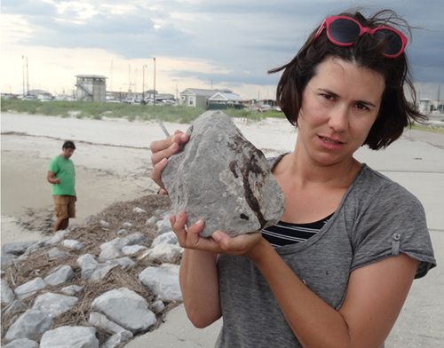 Helen White on a Gulf coast beach holding a jetty rock with oil residue on it. (Photo by Mike McNulty, Woods Hole Oceanographic Institution )