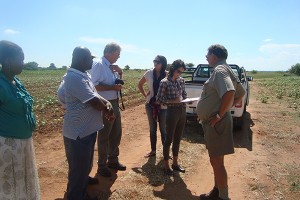 Master's degree students in fashion and apparel studies Leslie Siron (student on left, wearing white sweater) and Crescent Scudder (writing) talk with farmers in a cotton field in South Africa. Photo courtesy of Marsha Dickson