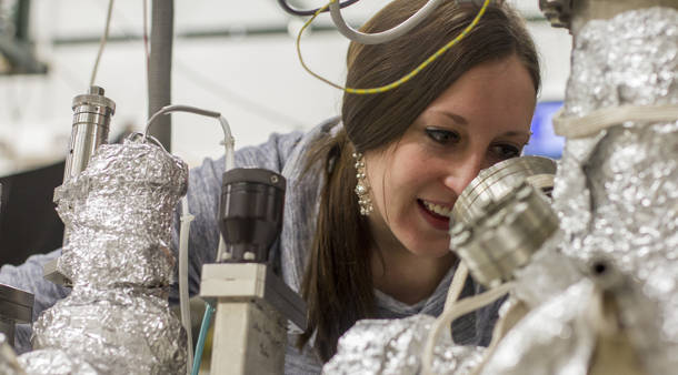 Calley Eads inspects a sample in the vacuum chamber to get it ready for measurement. (Photo credit: Kyle Mittan/UANews) 